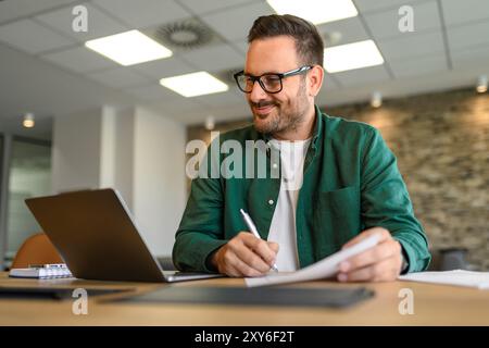 Portrait of financial analyst examining report and working on new strategies over laptop in office Stock Photo