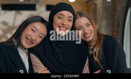 Friends diversity businesswomen Arabian Islamic Muslim girl businesswoman hijab cuddling hugging cuddle unity friendship multiracial office women Stock Photo