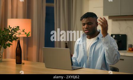 Angry mad stressed drunk alcohol addict African American man biracial male guy talking anger video call laptop chat distant online conflict conference Stock Photo