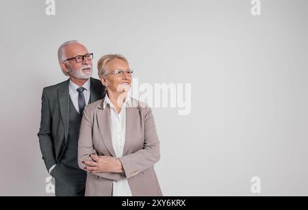 Senior executives in eyeglasses contemplating and looking away while standing over white background Stock Photo