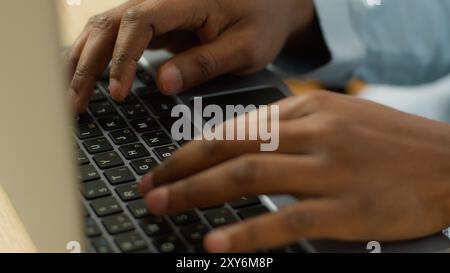 Unrecognizable biracial businessman student working studying with computer pc at table close up male African American user hands typing on laptop Stock Photo