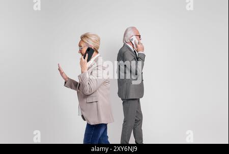 Side view of senior business executives discussing strategies over smart phones on white background Stock Photo
