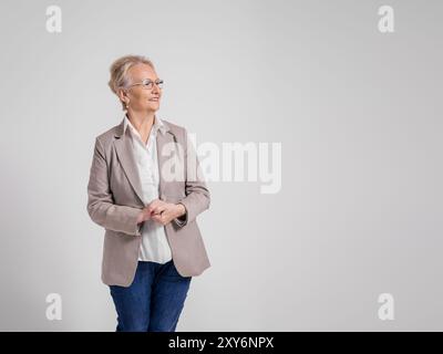Thoughtful senior female professional with hands clasped looking away over isolated white background Stock Photo