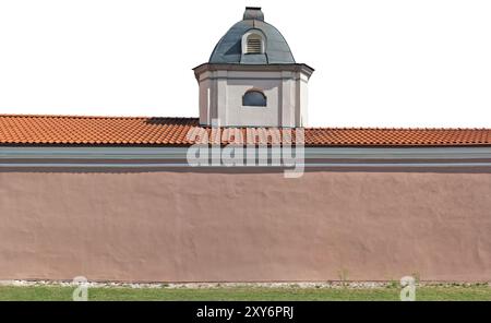 The wall of an ancient church with a red tiled roof and a small tower. Isolated on white Stock Photo