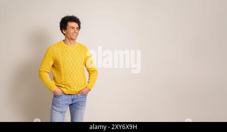 Smiling young businessman with hands in pockets contemplating and looking away on white background Stock Photo