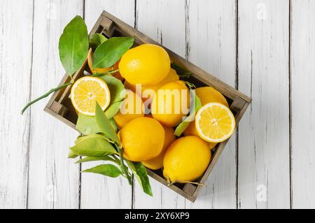 Fresh ripe yellow lemon fruits with leaves on rustic background Stock Photo