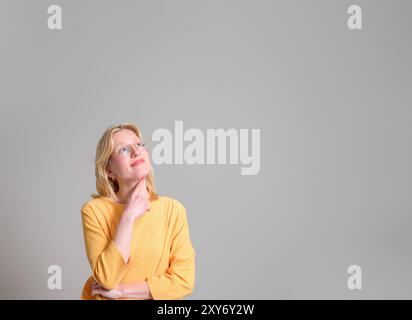 Thoughtful young businesswoman with hand on chin smiling and looking away against white background Stock Photo