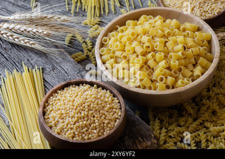 Various raw pasta with cutting board on stone background, uncooked food concept Stock Photo
