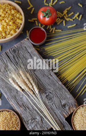 Various raw pasta with cutting board on stone background, uncooked food concept Stock Photo