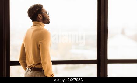 Single afro businessman looking out the window Stock Photo