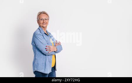 Portrait of old confident businesswoman with arms crossed smiling and standing on white background Stock Photo