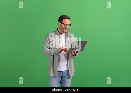 Portrait of happy handsome entrepreneur checking e-mails online over laptop against green background Stock Photo