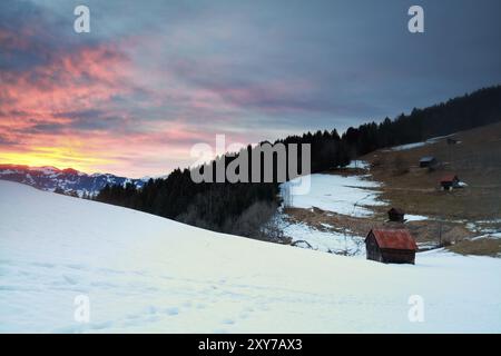 Dramatic sunset over snowy mountains and huts in Alps Stock Photo