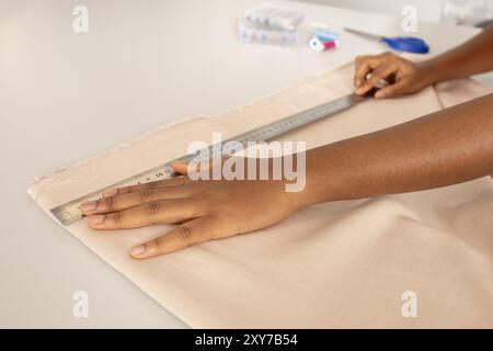 Unrecognizable seamstress woman using measuring tape on the fabric Stock Photo