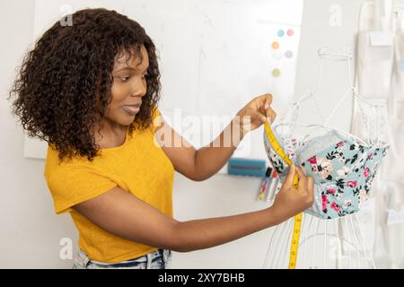 Woman tailor measuring dress on mannequin while working in sewing atelier Stock Photo
