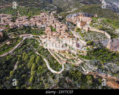 A picturesque medieval village with tiled roofs and a fortified fortress surrounded by green vegetation, aerial view, collegiate church on the hill, C Stock Photo