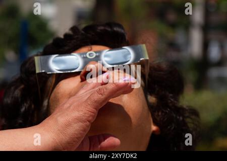 Mexico City, Mexico; 04 08 2024; A woman watching the total solar eclipse with a pair of solar glasses. Stock Photo
