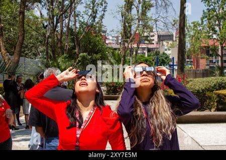 Mexico City, Mexico; 04 08 2024; Two women watching the total solar eclipse one with a welding galss and the othaer with a pair o special glasses. Stock Photo