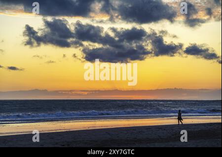 Young woman is walking along the beach at sunset Stock Photo