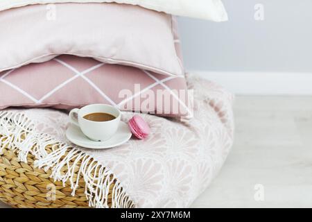 Pink and white pillows and cup of coffee and macaron on the wall background. Close up Stock Photo