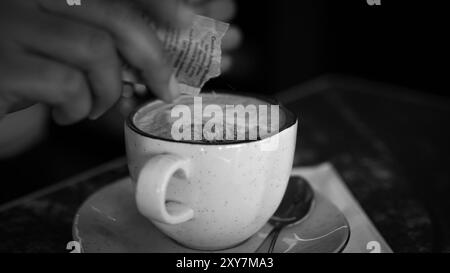 White ceramic cups of cappuccino with latte art Barista make coffee by pouring spills hot milk cream on black coffee .Black luxury coffee presentation Stock Photo