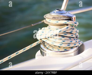 Sailboat detailed parts. Close up on winch and rope of yacht over blue sea. Yachting concept. Shallow depth of field Stock Photo