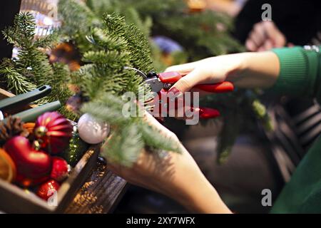 Cropped view of the family making christmas wreath from fir branches, christmas balls and pine cones on the wooden table Stock Photo