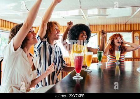 Multiethnic group of friends supporting team during a sport match at diner restaurant - Multiracial young people bonding and having fun, eating in a f Stock Photo