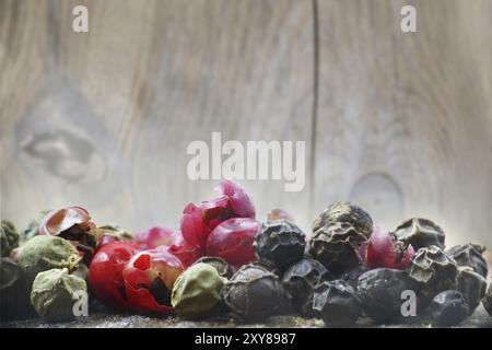 Colored peppers mix, close up, black, green and red in front of old wood, macro Stock Photo