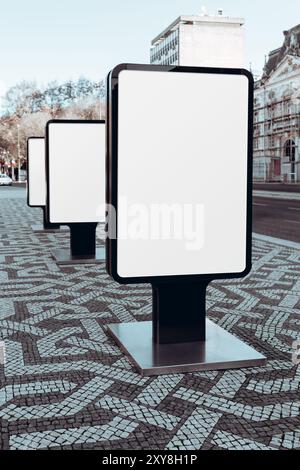 Series of blank digital billboards mockup in an urban outdoor setting, placed along a patterned sidewalk. The modern black-framed screens template are Stock Photo