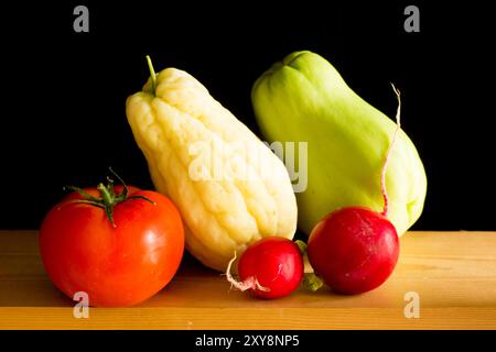 different and colorful vegetables on a wooden table, on black background. Stock Photo