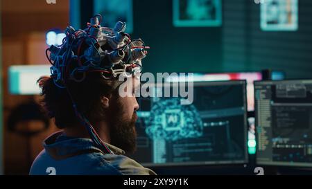 Developer using EEG headset device to upload his brain into computer, attaining immortality. Neuroscientist runs experiment, transfers consciousness into cyberspace, transhumanism concept, camera A Stock Photo