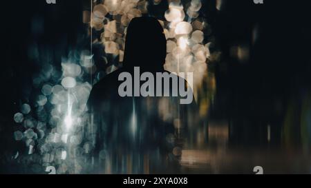 A double exposure of a spooky mysterious hooded figure. With bokeh and street lights. On a dark, moody night Stock Photo