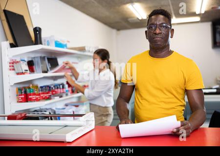 Employee of printing house checks the quality of printing in computer room Stock Photo