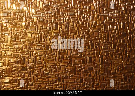 A close-up of shiny glass reflecting the warm, golden hues of sunset light. The abstract texture highlights the interplay of light and surface, creati Stock Photo