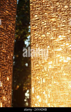 A textured glass surface catches the soft glow of sunset, featuring a vertical element aligned with the rule of thirds. The composition plays with lig Stock Photo