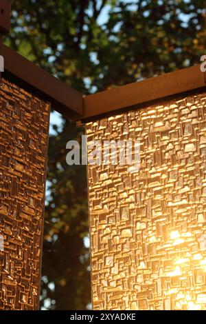 A textured glass surface catches the soft glow of sunset, featuring a vertical element aligned with the rule of thirds. The composition plays with lig Stock Photo