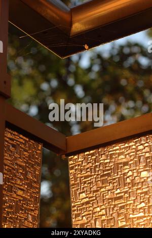 A textured glass surface catches the soft glow of sunset, featuring a vertical element aligned with the rule of thirds. The composition plays with lig Stock Photo
