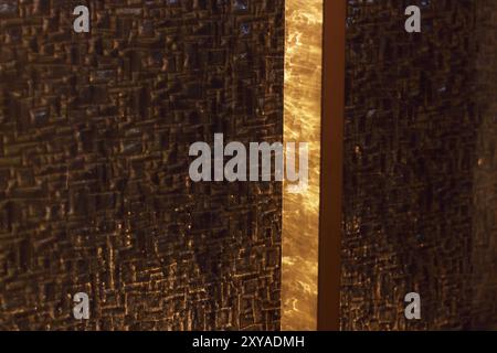A close-up of shiny glass reflecting the warm, golden hues of sunset light. The abstract texture highlights the interplay of light and surface, creati Stock Photo