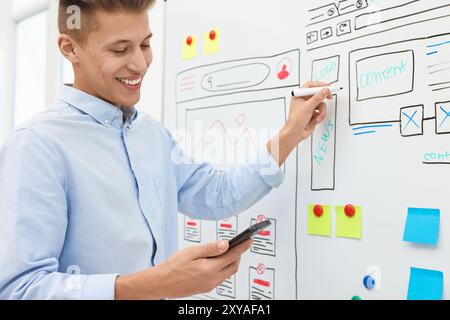 Developing UI design. Man drawing website wireframe on whiteboard indoors Stock Photo