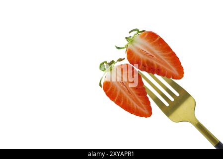 Two halves of a half-cut strawberry pinned on a golden fork isolated on a white background Stock Photo