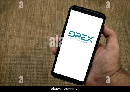 Sao Paulo, Brazil, April 16, 2024. Digital drex coin logo is seen on a smartphone over straw background in Brazil Stock Photo