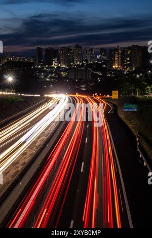 Trail of light caused by vehicular traffic in SP-294, Comandante Joao Ribeiro Barros Highway with buildings from downtown in the background, in Maríli Stock Photo