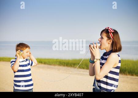 Kids having a phone call with tin cans on sea background Stock Photo