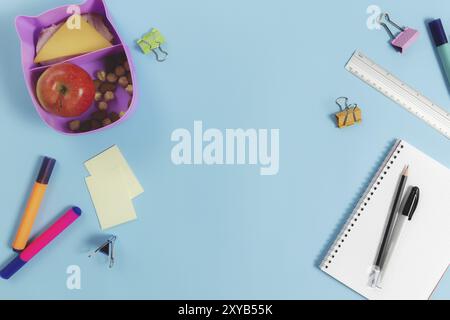 Primary school flat lay concept with assorted school supplies, notepad, pen, pencil, markets, stickers, paper clips and lunch box with sandwich, nuts Stock Photo