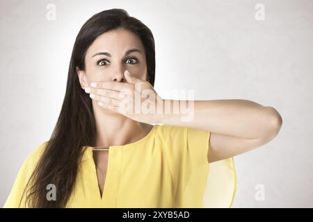 Female covering her mouth with her hand, isolated in grey Stock Photo