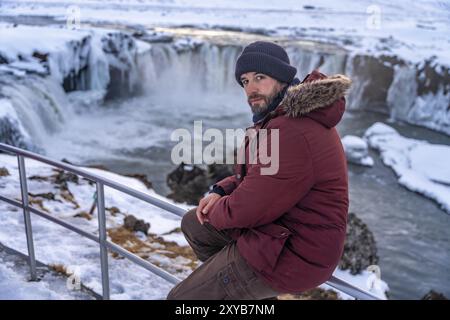 Portrait of a man hiker at frozen Godafoss waterfall at sunset in winter, Iceland, Europe Stock Photo