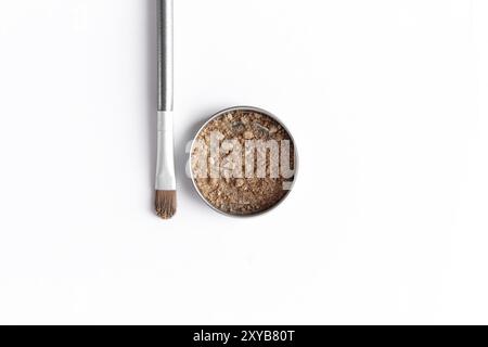 Light brown face shadow in container and eye shadow or make-up brush. Makeup concept flat lay on white background Stock Photo