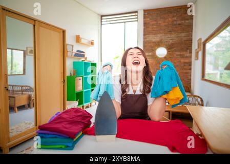 An Indonesian housewife is in a room with a pile of clothes and a pile of towels. She is yelling and seems to be in a bad mood Stock Photo