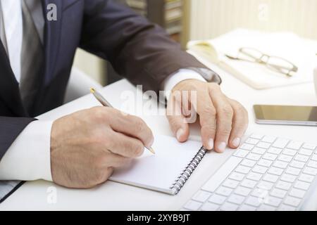 Male hands using modern computer and writing in a notepad business concept close up Stock Photo